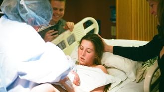 Vrouw die net bevallen is en haar baby in de armen krijgt