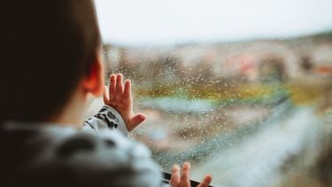 Kind dat naar buiten kijkt waar het regent