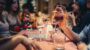 Een vriendengroep die wijn drinkt aan tafel