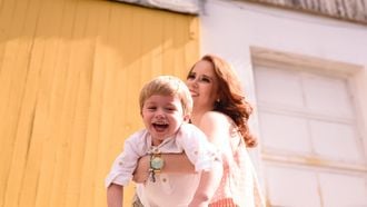 kleuter hangt in de armen van zijn moeder