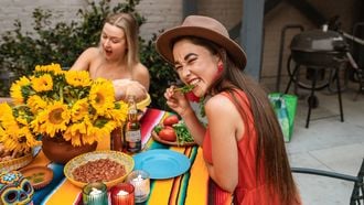 twee vrouwen in kleurrijke jurken eten een gezonde vegan maaltijd