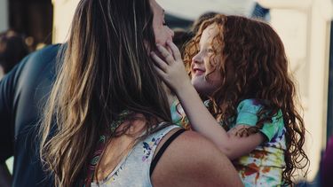 Moeder en dochter die knuffelen en grapjes maken over de waarheden rond moederschap