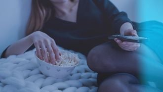 eten / vrouw eet popcorn terwijl ze tv kijkt