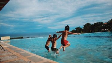 Drie kinderen die in een zwembad springen tijdens een relaxte vakantie