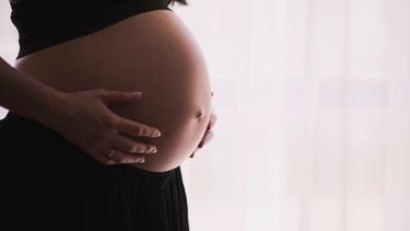 Zwangere vrouw die aan haar buik voelt wat de ligging van haar baby is voor de bevalling