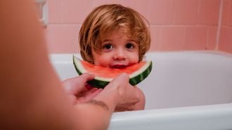 peuter eet watermeloen in bad
