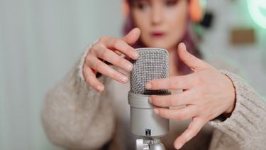Vrouw beweegt haar nagels over een microfoon en doet ASMR