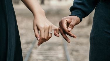 Vrouw en mannen hand houden elkaars pink vast. Met een liefdesformule de lengte van je relatie bepalen