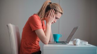 Vrouw zit met beide handen voor haar laptop; alsof zwangerschapsdementie toeslaat