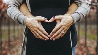 Stelletje dat de handen op de zwangere buik van devrouw houdt in de vorm van een hart
