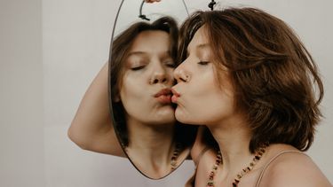 Vrouw kust haar spiegelbeeld, haar lichaam wordt geen frenemy