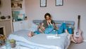 Stelletje dat samen op bed ligt en pizza eet