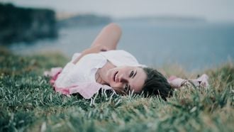 vrouw ligt in het gras te relaxen om een mommy burn-out te voorkomen