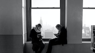 Koppel allebei op telefoon, technologie beïnvloedt de relatie