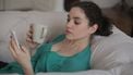 Vrouw die op haar telefoon leest dat ze voor haar veertigste overgangsklachten van de perimenopauze kan aanpakken