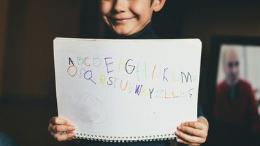 alfabet op een blaadje geschreven door een jongetje