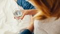 vrouw houdt glas met water vast om te hydrateren