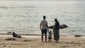 Gezin dat samen de wereld over reist en nu op een strand staat kijkend naar de zee