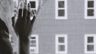 hand tegen raam en regen