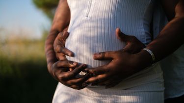 Zwangere vrouw die samen met haar partner haar buik vasthoudt en affirmaties opzegt voor de bevalling