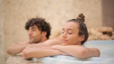 Vrouw en man liggen ontspannen in een hot tub, en doen deze herkenbare dingen in een spa