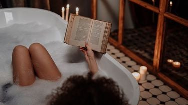 Vrouw die het beste weekend heeft en lekker een boek leest in bad