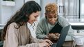 Twee vrouwen die samen naar iemands salaris kijken op de laptop