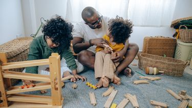 Kinderen aan het spelen met speelgoed en hun vader