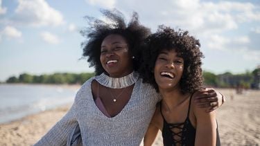 Twee vriendinnen die samen lachen op het strand