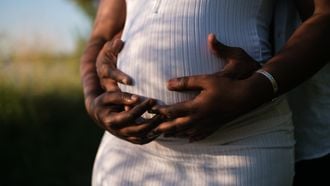 Zwangere vrouw die samen met haar partner haar buik vasthoudt en affirmaties opzegt voor de bevalling