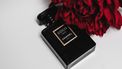 Zwart parfumflesje Coco Chanel met rode roos. Lessen van coco chanel