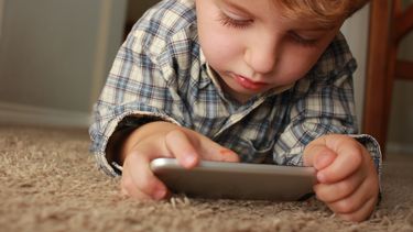 kind zit gehoorzaam op telefoon te spelen op basis van het montessori stappenplan