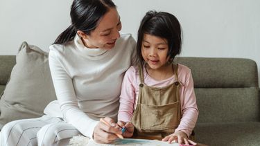 Kind dat met haar moeder aan het tekenen is