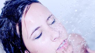 Vrouw die onder de douche staat en zich afvraagt hoe vaak ze zich moet douchen