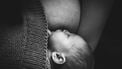 Zwart wit foto van baby die borstvoeding krijgt, waarschijnlijk nachtvoeding
