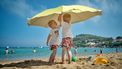 kinderen onder een paraplu in de zon