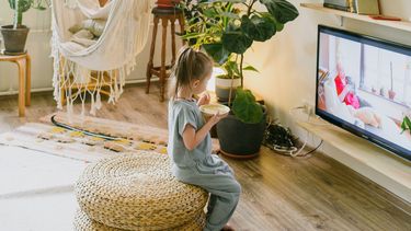 Kind dat van bamboe kinderservies eet en tv kijkt