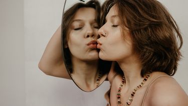 Vrouw kust haar spiegelbeeld, haar lichaam wordt geen frenemy