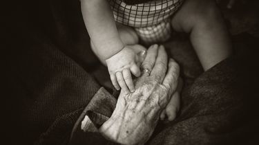 hand van grootouder en kind
