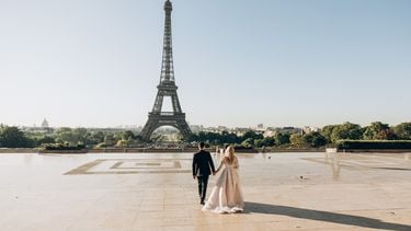 Net getrouwd koppel voor de Eiffeltoren zeggen romantische zinnetjes in andere talen tegen elkaar