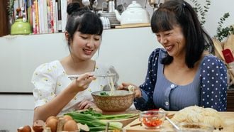 Twee Aziatische vrouwen eten soep met stokjes. Soep voor herstellen postpartum lichaam