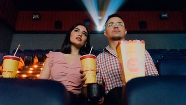 Koppel zit met popcorn en frisdrank in bioscoop. Film past bij sterrenbeeld