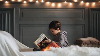 Jongetje dat in bed een boek leest