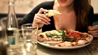 Vrouw die een pizza eet met gesmolten kaas
