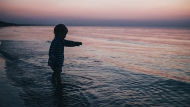 Kind met het sterrenbeeld waterman die in de zee staat