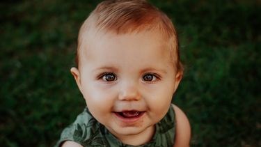 Een baby die in de camera kijkt en lacht met een Portugese babynaam