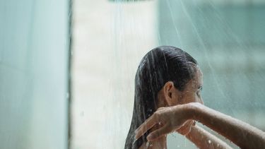 Vrouw die onder de douche staat en haar haar wast