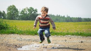 Een jongetje dat in de plassen springt