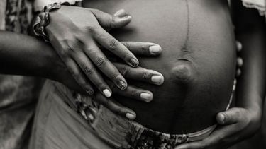 Buik van een zwangere vrouw met linea nigra, een lichamelijke verandering die ook na de bevalling kan blijven