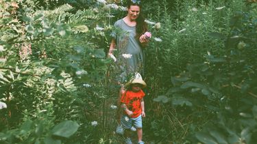 Moeder die met haar kind door de tuin loopt en laat zien hoe je groen kunt leven